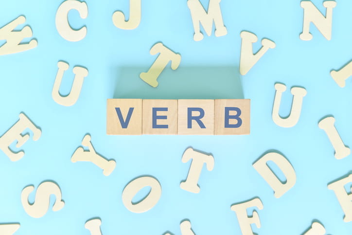 The alphabet spread out in the background with wooden blocks spelling out the word: "Verb."