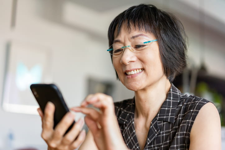 A woman smiling at her cellphone.
