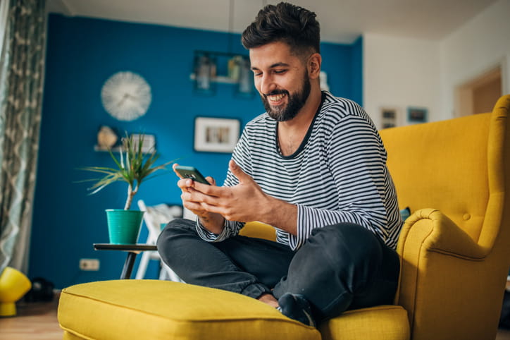 A man smiling at his cellphone learning english