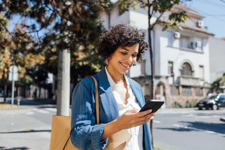 A woman smiling at her phone.