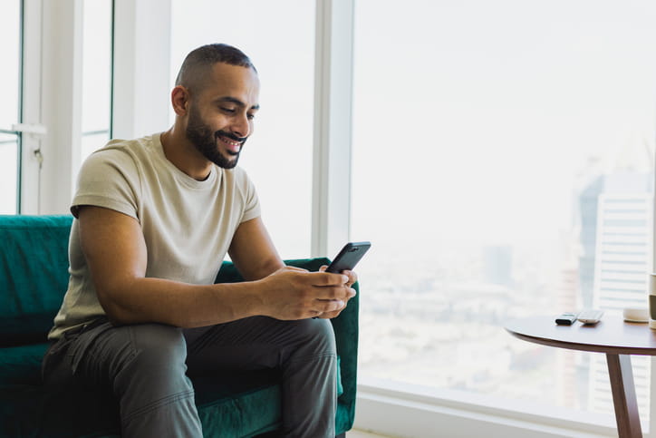 A man smiling at his phone learning english